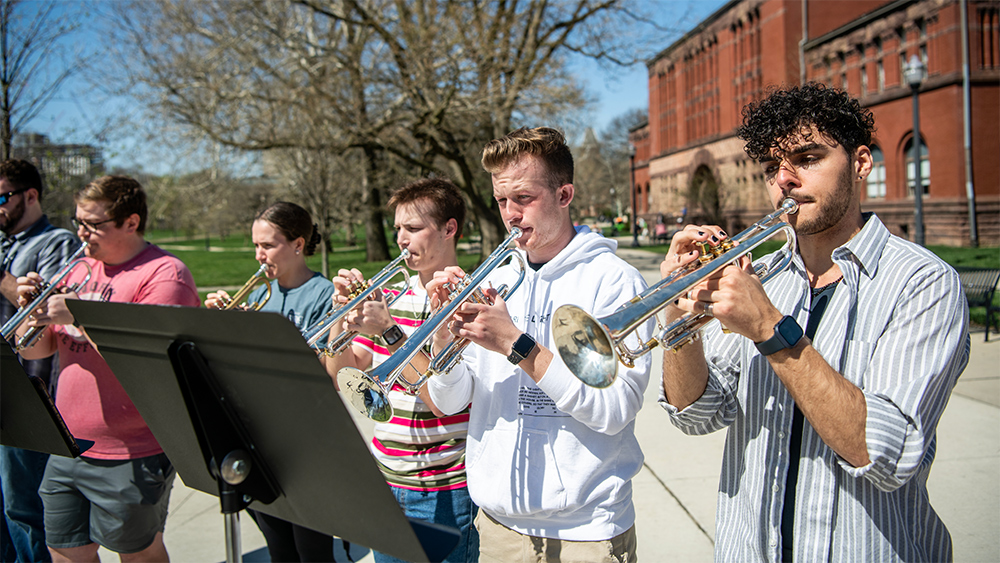 The OSU Trumpet Ensemble, a class within the School of Music in the College of Arts and Sciences, practices outdoors near the Oval and Hayes Hall on a sunny spring day.